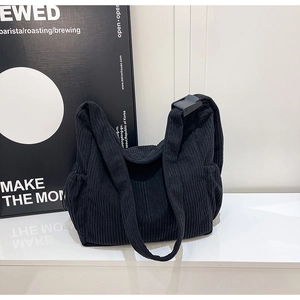 Detail of black corduroy crossbody tote bag showing adjustable strap buckle and texture