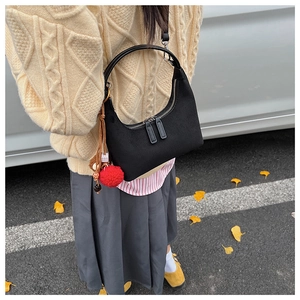 Détail du sac hobo noir en demi-lune avec pompon rouge et double fermeture éclair