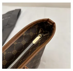 Gros plan sur la fermeture éclair dorée fluide et la texture monogramme du sac cabas