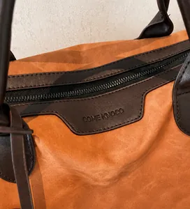 Close-up of caramel suede tote bag with brown leather handles and top zipper detail