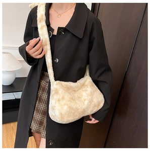 Détail du sac bandoulière beige en fausse fourrure douce porté sur un manteau de laine noir
