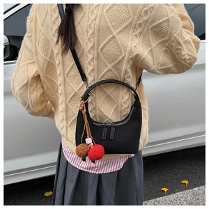 Détail du sac demi-lune noir avec double fermeture éclair et charm sur le mannequin