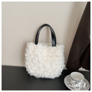 Dettaglio di una borsa a secchiello in pile bianco con manici in pelle nera a contrasto