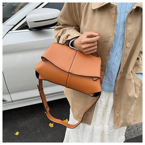 Detail of cognac pebbled leather handbag featuring unique geometric folded design and stitching