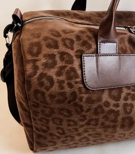Dettaglio borsa da viaggio marrone leopardata con trama in camoscio e manici in pelle