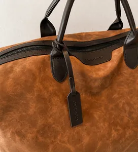 Macro detail of brown suede tote bag featuring reinforced leather handles and brand tag