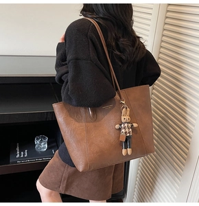 Close-up of brown faux leather tote bag featuring a cute houndstooth bunny charm accessory