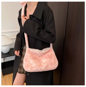 Pink plush bucket bag with fuzzy texture and matching strap on a black coat outfit