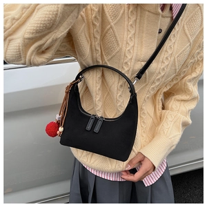 Détail du sac hobo en daim noir avec pompon rouge et accessoire à carreaux chic