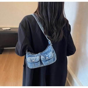 Detailed view of vintage blue denim crescent shoulder bag with pockets and silver snaps