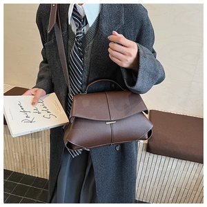Detail of dark brown lychee grain leather handbag with chic metal buckle and flap design