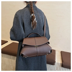 Detail view of brown crossbody bag with white stitching and vintage folding flap design