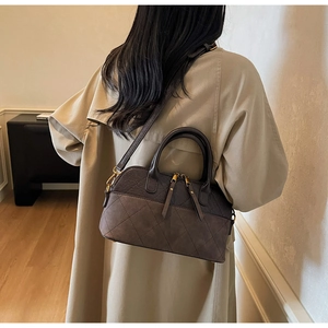 Lifestyle view of brown quilted shell bag worn crossbody over a classic trench coat