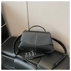 Detail of black pebbled leather handbag with contrast white stitching and adjustable strap
