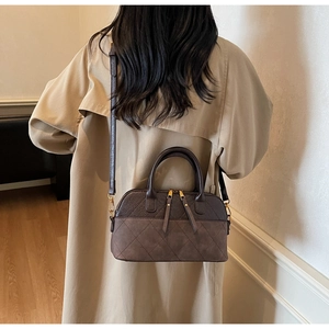 Model wearing a brown quilted shell bag in a beige trench coat for a vintage look