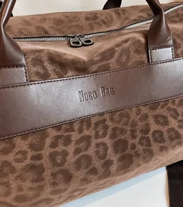 Dettaglio ravvicinato della borsa da viaggio leopardata con finiture in pelle e logo