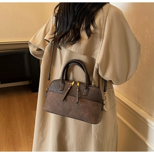 Detail of vintage brown quilted shell bag featuring fringe zippers and a matte finish