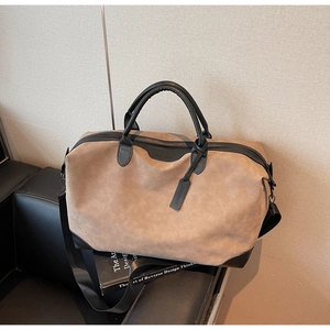 Dettaglio borsa da viaggio in pelle scamosciata marrone con manici in pelle nera