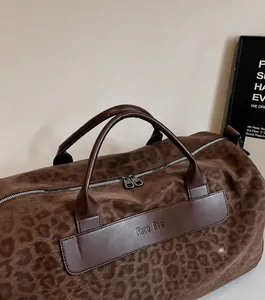 Dettaglio della borsa da viaggio leopardata con manici in pelle e doppia cerniera in metallo