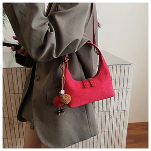 Détail d'un sac sous le bras en daim rouge en demi-lune avec perles et pompon décoratifs