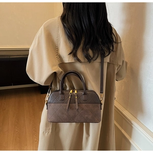 Model wearing a coffee brown quilted shell bag with leather patchwork and gold zippers