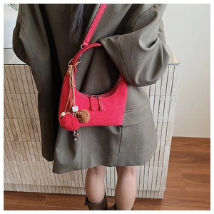 Détail du sac croissant en daim rouge avec fermetures éclair doubles et pompons déco
