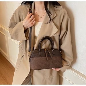 Detailed view of brown quilted shell crossbody bag on a model wearing a beige trench coat