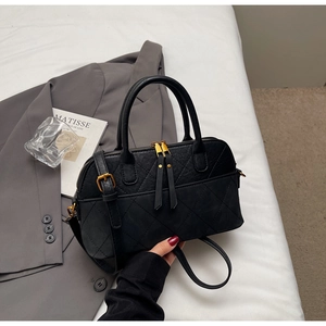 Close-up of vintage black shell-shaped handbag with diamond quilting and gold hardware