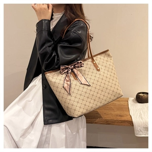Détail d'un grand sac cabas beige avec motifs géométriques café et écharpe à pois roses