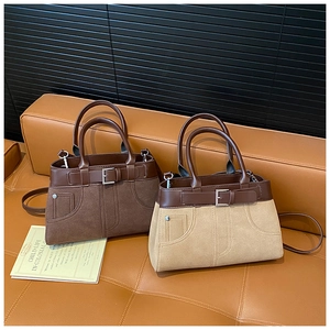 Close-up of vintage leather tote bags in dark brown and khaki on a leather sofa