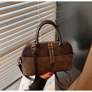 Detail view of retro shell bag with quilted texture, dual zippers and adjustable strap