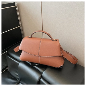 Close-up of caramel brown retro shoulder bag showing textured lychee leather and fold flap