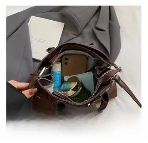 Spacious interior of brown leather handbag showing phone and cosmetics in detail
