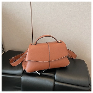 Detail shot of tan leather handbag with white cross stitching and lychee grain texture