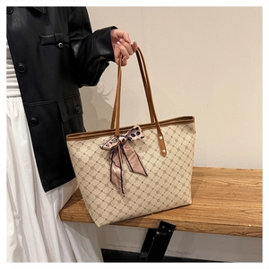 Détail d'un grand sac cabas beige avec motifs géométriques et décoration de foulard