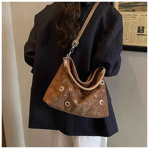 Détail d'un sac hobo en daim marron avec œillets métalliques et bandoulière réglable