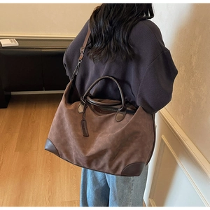 Dettaglio di una borsa tote grande in pelle scamosciata marrone con manici in cuoio
