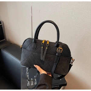 Detail of black quilted boston bag featuring bronze hardware and leather tassel zipper