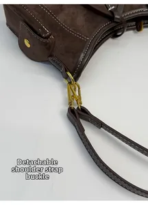 Detail of detachable shoulder strap buckle on dark brown suede and leather bag