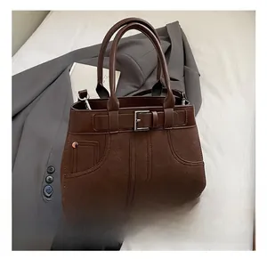 Detail of vintage matte brown crossbody bag with metal buckle and round handles