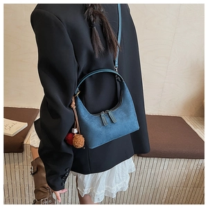 Détail du sac demi-lune en daim bleu avec zips argentés et breloques en peluche