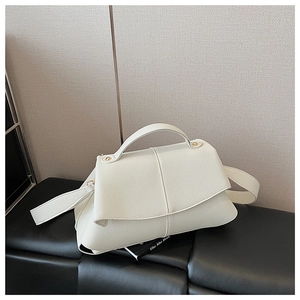Detail of white lychee texture shoulder bag with gold hardware and top handle on a bench