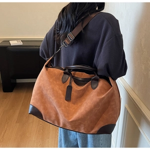 Vista dettagliata di una grande borsa tote da viaggio marrone indossata da modella