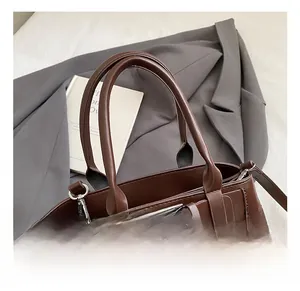 Detailed close-up of brown leather and matte suede stitching on vintage tote bag