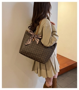 Détail du sac cabas marron foncé à motif géométrique et nœud léopard rose sur la sangle
