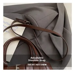 Detail of adjustable leather shoulder strap with silver metal buckle on a brown bag