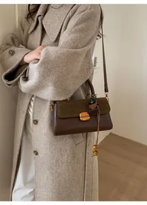 Detail of crossbody bag featuring brown leather and olive suede stitching with gold lock