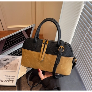 Detail of color-block quilted handbag with top handles and bronze hardware accessories
