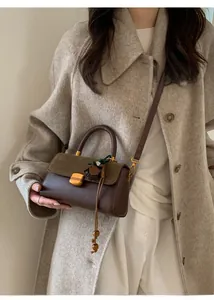 Detail of vintage crossbody bag with olive suede, brown leather, and tassel charm