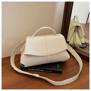 Close-up of cream-colored pebble leather texture with gold metal hardware and stitching